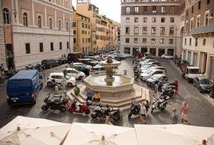 a city street with a fountain and parked cars at Repetita Juvant in Rome