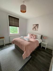a bedroom with a bed with pink pillows and a window at The Beverley Suite in Sheringham