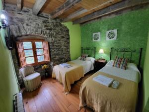 a bedroom with two beds in a room with green walls at Hotel Rural LA CÁRCEL in Murias de Paredes