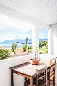 a wooden table on a porch with a potted plant on it at Pousada Aconchego Recanto Canto Do Mar in Bairro da Enseada