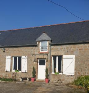 a brick house with white doors and a black roof at Wildberry cottage in Orgères-la-Roche