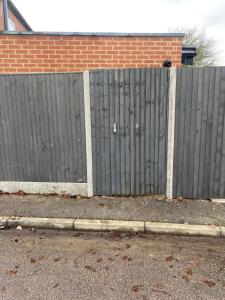 a wooden fence in front of a brick building at Lovely and Modern Studio Apartment. in Borehamwood