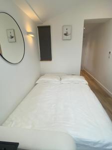 Cama blanca en habitación con espejo en Lovely and Modern Studio Apartment., en Borehamwood