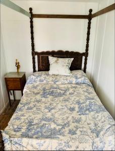 a bed with a blue and white comforter and a pillow at A unique, off-grid Eco Friendly Beach House. in Wolferton