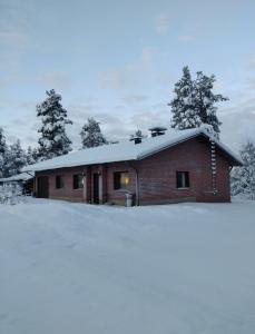 une maison en briques avec un toit recouvert de neige dans l'établissement Laplands Hillside House, à Rovaniemi