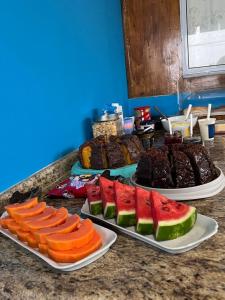 un mostrador con tres platos de frutas y hortalizas. en Pousada Pé Na Areia - ilha do mel, en Paranaguá