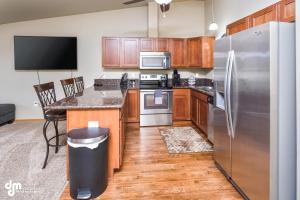 a kitchen with wooden cabinets and a stainless steel refrigerator at Tranquil Stay at Settlers Bay, Newly Furnished! in Wasilla