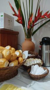 two baskets of bread on a table with a vase at Pousada Ponta da Baleia in Barra Grande