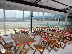 um grupo de mesas e cadeiras numa sala com janelas em FRANCIS HOTEL MAR em Caraguatatuba