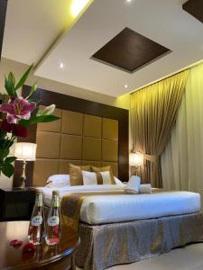 a bedroom with a large bed with two bottles on a table at Raihana for serviced apartment in Jeddah +22 photos