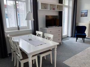 einen weißen Esstisch mit Stühlen und einen TV in der Unterkunft Ferienwohnung Windlicht in Kühlungsborn