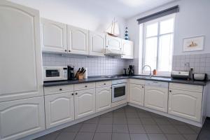 eine weiße Küche mit weißen Schränken und einem Fenster in der Unterkunft Ferienwohnung Windlicht in Kühlungsborn