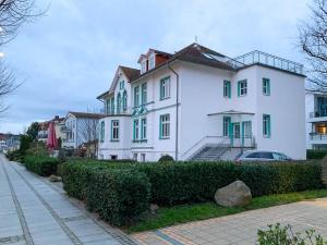 ein weißes Haus mit grünen Fenstern und einer Straße in der Unterkunft Ferienwohnung Windlicht in Kühlungsborn