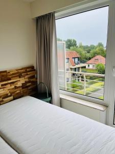 1 dormitorio con cama y ventana grande en duinpark62: gezellig 3 slaapkamer-appartement inclusief garage, en Oostduinkerke