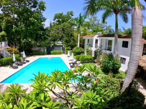 a swimming pool in front of a house with a palm tree at Coral Blanco Hotel in Sosúa