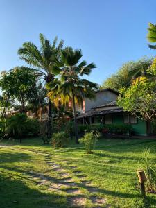 a house with palm trees in front of a yard at Pousada Marezia Top 5 na Linha Verde in Porto de Sauipe