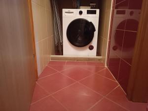 uma máquina de lavar roupa na casa de banho com piso em azulejo vermelho em Apartment King em Seliste Dreznicko