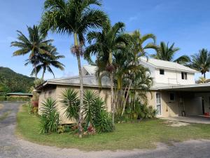 a house with palm trees in front of it at Konini Villa in Rarotonga