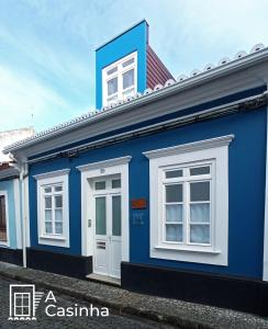 A Casinha في أنغرا دو إِراويزو: مبنى باللونين الأزرق والأبيض مع نوافذ بيضاء