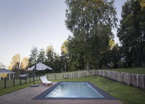 a pool in a yard with a chair and an umbrella at Das Dorf Hotel in Pucón