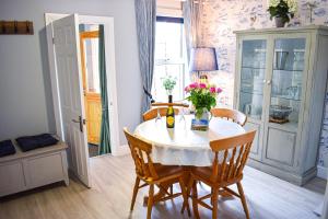 a dining room with a table with chairs and flowers on it at Curlew Cottage - Suffolk Coastal Escapes in Pakefield