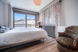 a bedroom with a bed and a window and a chair at Chalet Nessa in Combloux