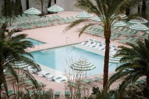 an overhead view of a hotel pool with chairs and palm trees at NoMad Las Vegas in Las Vegas