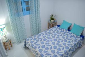 a bedroom with a blue and white bed with blue pillows at LOGEMENT AZUL à l'ombre du bambou 1 à 3 pers, Réserve Cousteau in Le Gosier