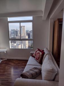 a living room with a couch and a large window at Flat na Rua XV 2107 in Curitiba