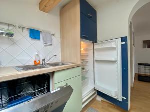 a kitchen with a sink and an open refrigerator at Ferienwohnung Stadlmann in Ebensee