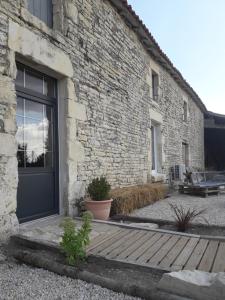 a brick building with a door and a wooden porch at Au Domaine du Petit Cercoux in Saint-Saturnin-du-Bois