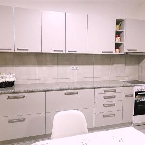 a white kitchen with white cabinets and a white chair at Andrej's Village House 