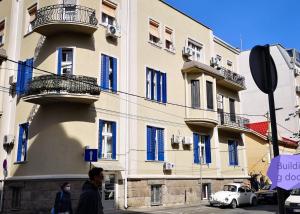 ein Gebäude mit blauen Fenstern und einem weißen Auto auf einer Straße in der Unterkunft Bibi's apartment in Belgrad