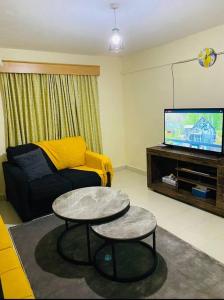 a living room with a couch and a table and a tv at Stylish centrally located apt: secure,WiFi&parking in Meru