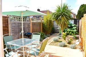 a patio with a table and chairs and an umbrella at Curlew Cottage - Suffolk Coastal Escapes in Pakefield
