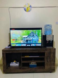 telewizor z płaskim ekranem siedzący na szczycie drewnianego centrum rozrywki w obiekcie Stylish centrally located apt: secure,WiFi&parking w mieście Meru
