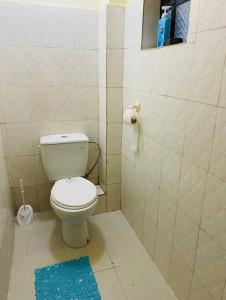 a bathroom with a white toilet and a blue rug at Stylish centrally located apt: secure,WiFi&parking in Meru