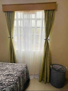 a bedroom with a bed and a window with curtains at Stylish centrally located apt: secure,WiFi&parking in Meru