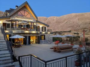 a large house with a patio with tables and umbrellas at Chalet de Charme, Cedars, Lebanon, Terrace Floor in Al Arz