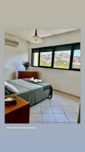 a bedroom with a bed and a table and windows at Thedreamlifehouse in Anavissos