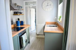 a kitchen with a sink and a clock on the wall at Curlew Cottage - Suffolk Coastal Escapes in Pakefield