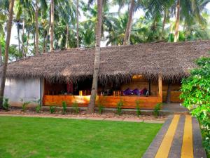 a house with a straw hut with palm trees at Agonda Paradise in Agonda