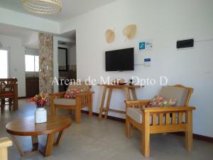 Il comprend un salon doté d'une télévision, de chaises et d'une table. dans l'établissement Arena de Mar - Dpto D, à Mar de las Pampas