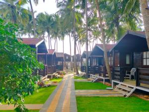 a row of houses with palm trees in the background at Agonda Paradise in Agonda