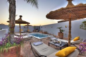 an outdoor patio with a pool and umbrellas at Riad Awa in Marrakesh