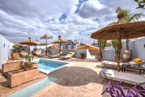 een patio met een zwembad en parasols bij Riad Awa in Marrakesh