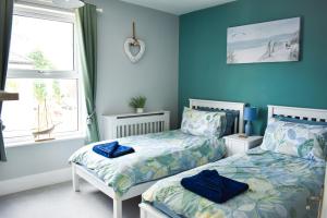 two beds in a bedroom with blue walls at Curlew Cottage - Suffolk Coastal Escapes in Pakefield