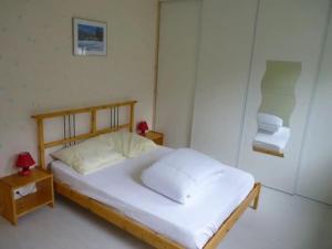 een slaapkamer met een bed met witte lakens en 2 tafels bij Maison lumineuse et spacieuse avec terrain in La Bourboule