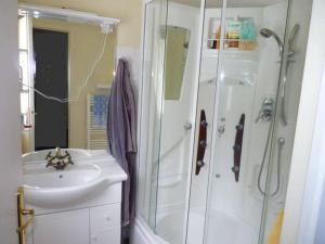 een witte badkamer met een wastafel en een douche bij Maison lumineuse et spacieuse avec terrain in La Bourboule
