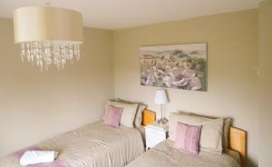 1 dormitorio con 2 camas y lámpara de araña en Woldsend en Moreton in Marsh